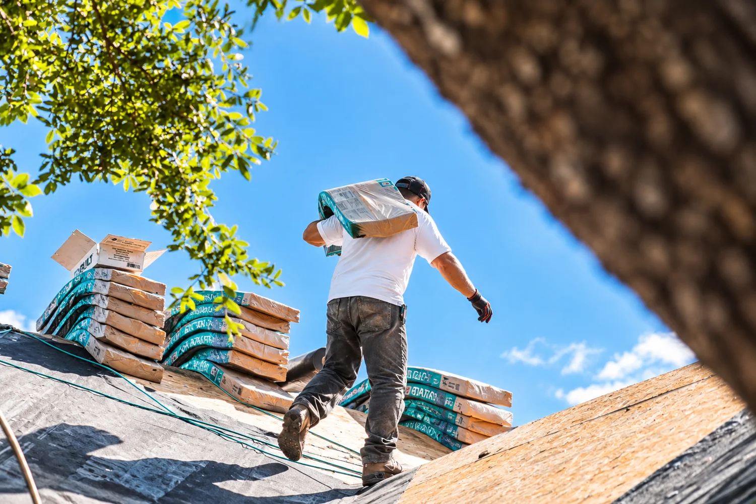 Roofer carrying a bundle of shingles onto the roof